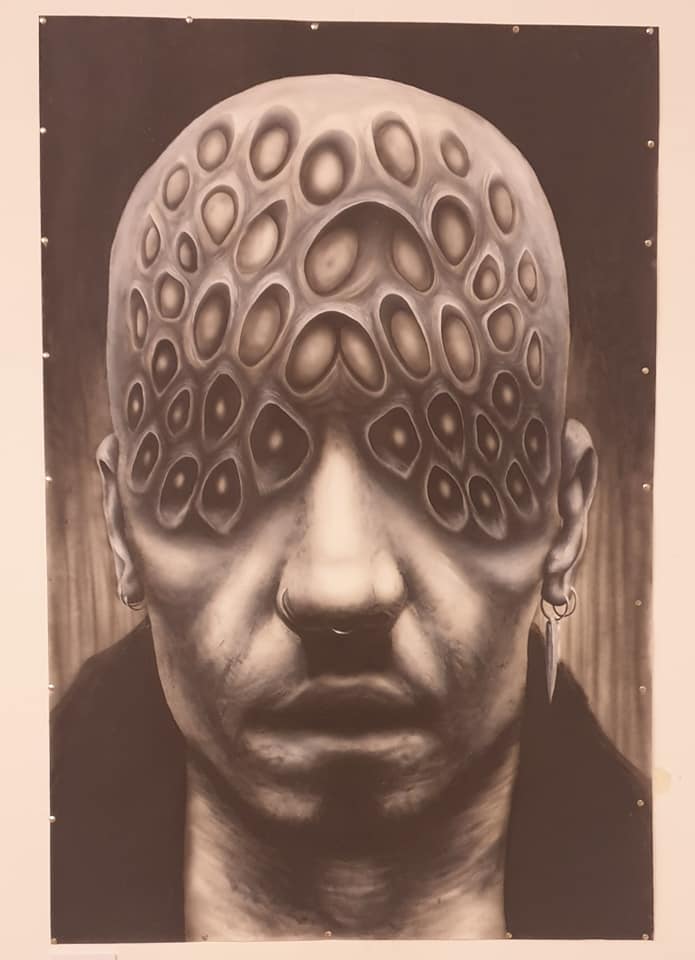 A black and white painting showing a surreal male face covered in strange orb shapes from the eye level up onto a bald head